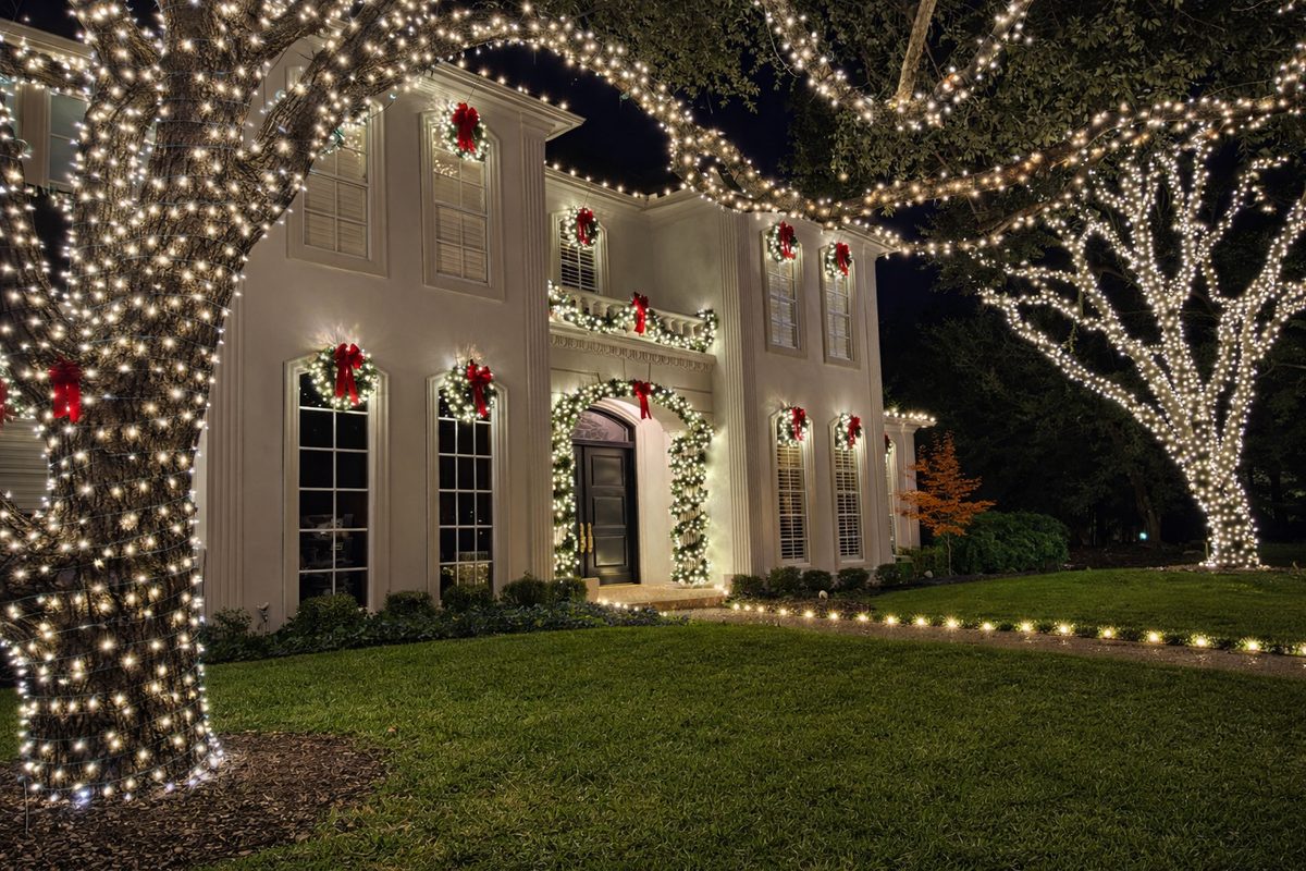 Warm-white holiday lighting on trees and home façade